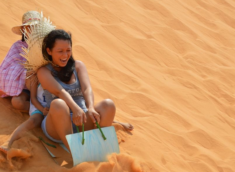 Du khách trượt cát tại đồi cát Mũi Né trong tour Phan Thiết 30/4